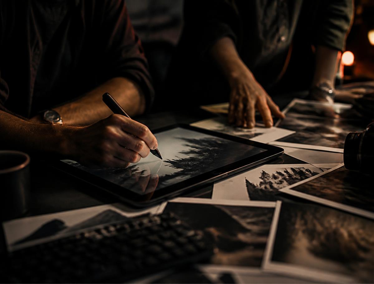 Designers reviewing printed frames and sketching on a tablet in a dark studio